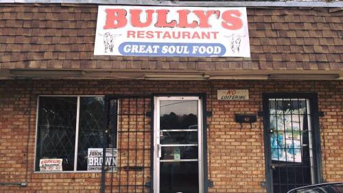 Exterior of Bully's Restaurant, featuring a sign that reads "Great Soul Food" and a brick facade. No loitering sign visible.