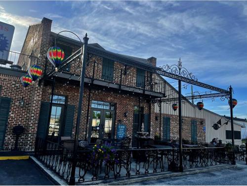 A brick building with green shutters and colorful hot air balloon decorations, featuring an outdoor seating area.