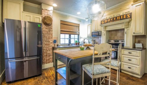 A modern kitchen featuring a stainless steel fridge, wooden island, and rustic decor with a "Groceries" sign.