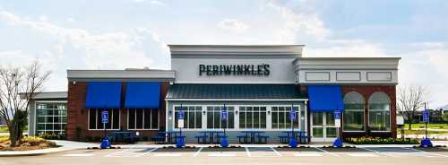 Exterior of Periwinkle's restaurant with blue awnings and outdoor seating, under a clear sky.