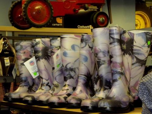 A row of colorful floral rain boots displayed on a shelf in a store.