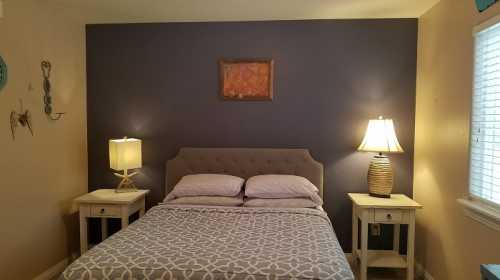 Cozy bedroom with a gray accent wall, a bed with patterned bedding, and two bedside lamps on wooden tables.