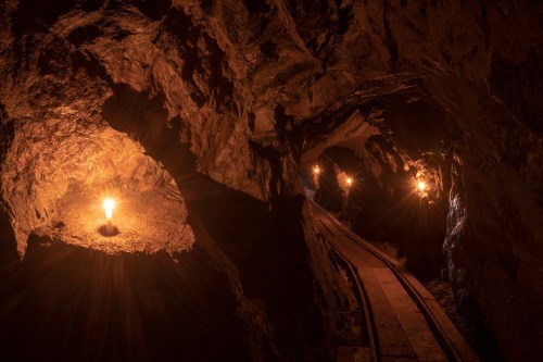Dimly lit underground mine with rocky walls and glowing lights illuminating the path.
