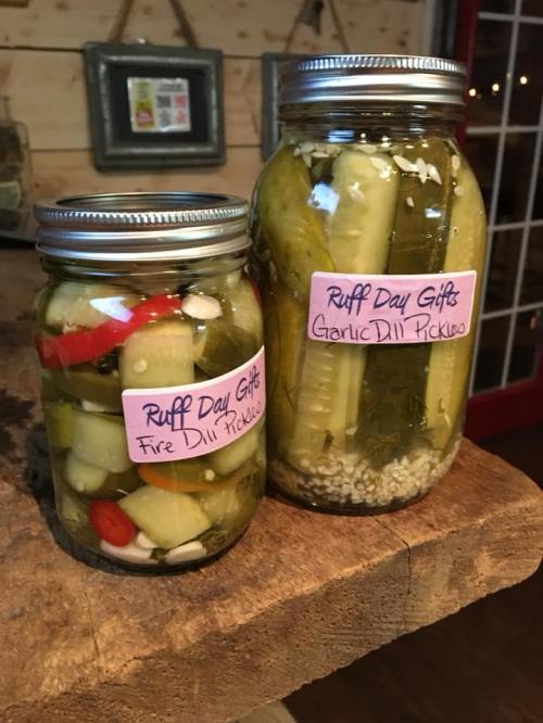 Two jars of pickles on a wooden surface, labeled "Fire Dill Pickles" and "Garlic Dill Pickles."