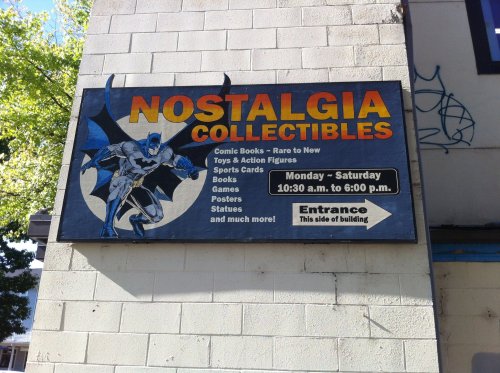 Sign for "Nostalgia Collectibles" featuring Batman, listing comic books, toys, games, and more. Open Monday to Saturday.