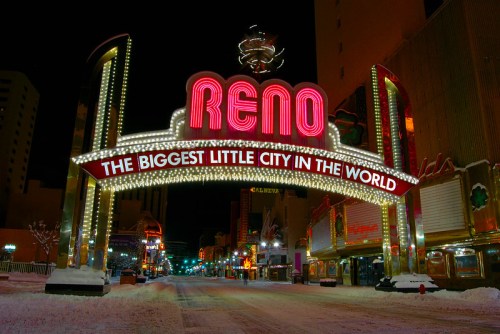 Neon sign for Reno, "The Biggest Little City in the World," illuminated at night with snow-covered streets.