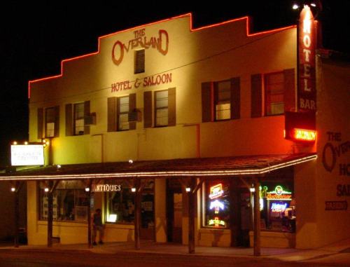 Historic hotel and saloon at night, illuminated with neon lights, featuring a bar and antique shop.