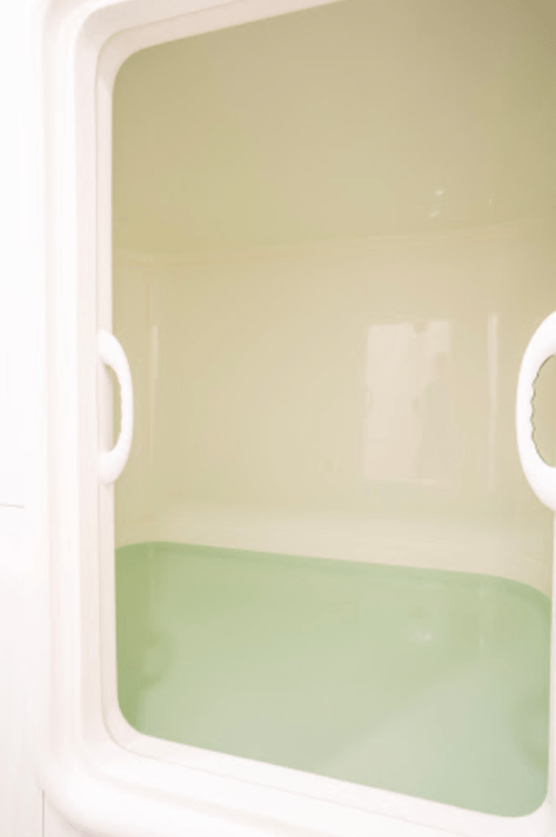 A clean, empty shower enclosure with a light green water surface and smooth white walls.