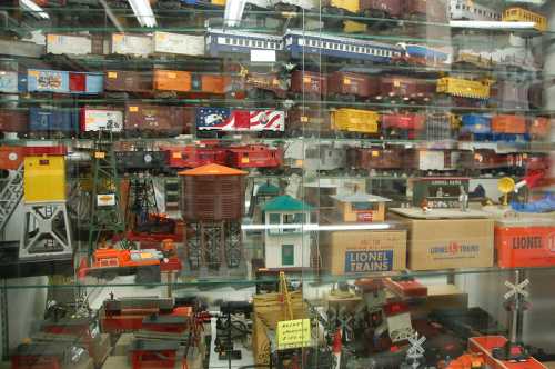 A display case filled with various model trains, train cars, and accessories in vibrant colors.