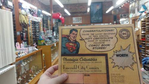 A vintage comic book store interior with a Superman gift certificate in the foreground.