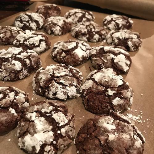 A tray of freshly baked chocolate crinkle cookies dusted with powdered sugar.