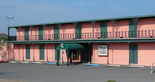 A pink two-story building with green shutters and a green awning, featuring a sign that reads "Casino."