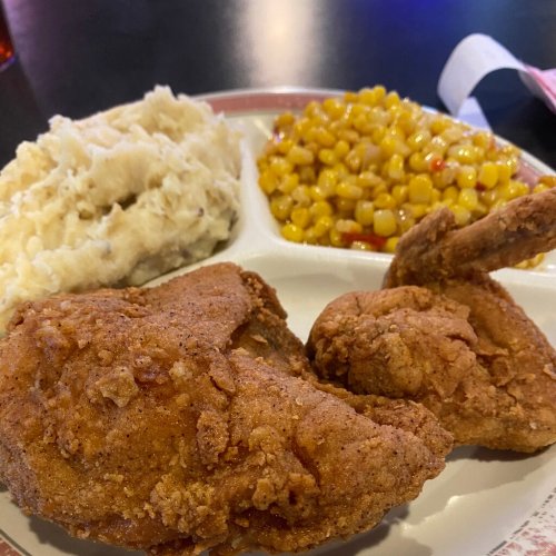A plate featuring fried chicken, mashed potatoes, and corn with peppers.