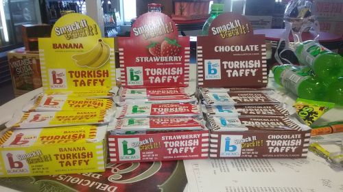 Display of Turkish taffy boxes in banana, strawberry, and chocolate flavors on a table.