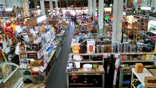 A bustling market filled with various goods, shelves stocked with products, and shoppers exploring the aisles.