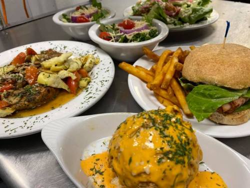 A variety of dishes including a burger, fries, salads, and a colorful vegetable plate on a table.