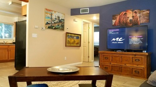 Cozy living space with a wooden coffee table, TV, and artwork on the walls, featuring a bear and scenic landscapes.