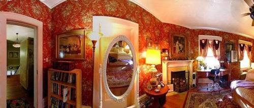 Cozy room with floral wallpaper, a mirror, fireplace, bookshelves, and warm lighting, creating an inviting atmosphere.