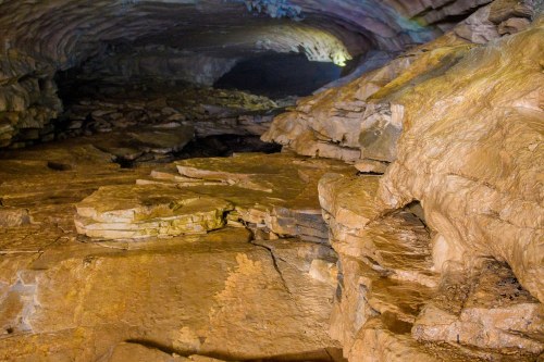 A dimly lit cave interior with rocky formations and uneven stone surfaces.