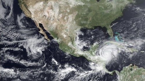 Satellite image showing a hurricane near the Gulf of Mexico, with surrounding clouds and landmasses of North America.