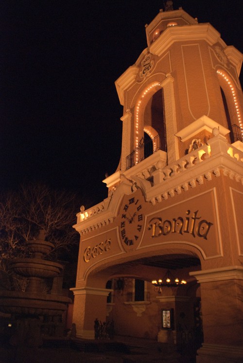 The illuminated entrance of Casa Bonita at night, featuring a clock and ornate architectural details.