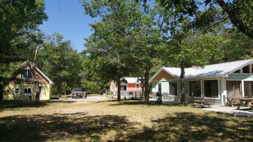 A sunny outdoor scene featuring several colorful cabins surrounded by trees and a grassy area.