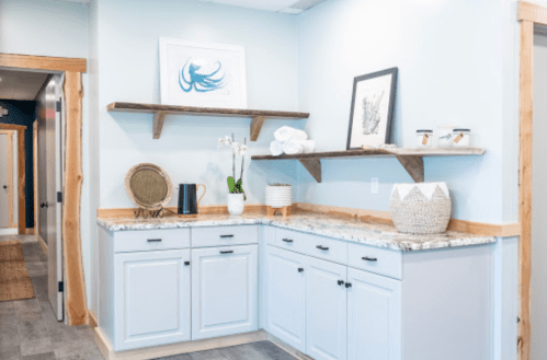 A light blue corner with shelves, decorative items, and a granite countertop in a modern interior space.