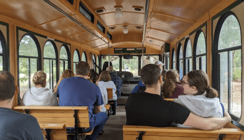 Interior of a trolley with passengers seated, facing forward, enjoying a ride through a scenic area.