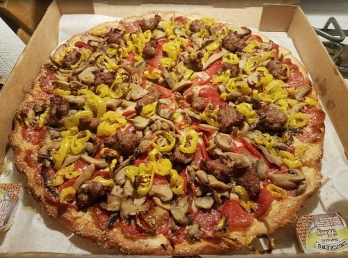 A large pizza topped with pepperoni, sausage, mushrooms, and yellow peppers in a pizza box.