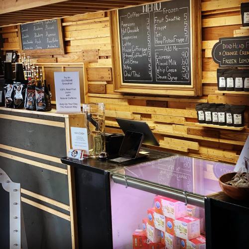A cozy café interior featuring a wooden menu board, coffee counter, and various drink options displayed.