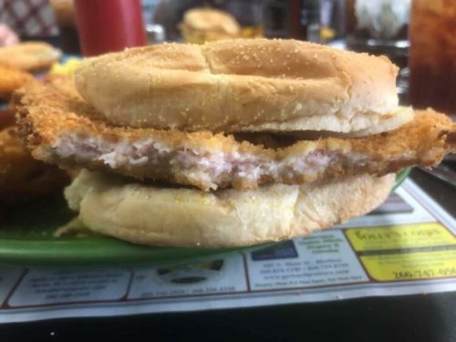 A close-up of a fried chicken sandwich with two pieces of bread and a crispy chicken fillet in between.