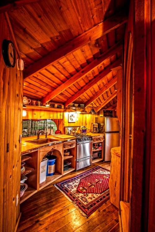 Cozy wooden kitchen with a high ceiling, rustic decor, and a warm atmosphere, featuring a stove and wooden cabinets.