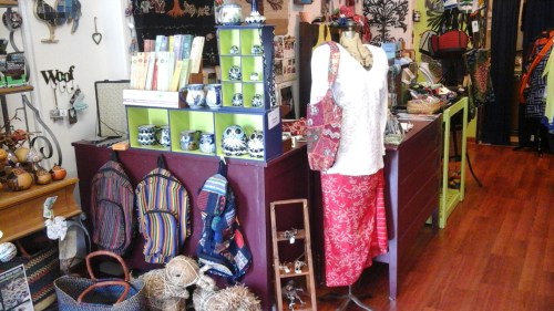 A colorful shop interior featuring a display of bags, accessories, and decorative items on shelves and tables.