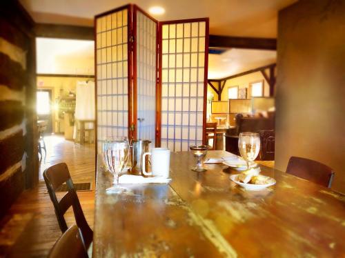 A rustic dining table set with glassware and a plate, with a room divider in a cozy, warmly lit interior.