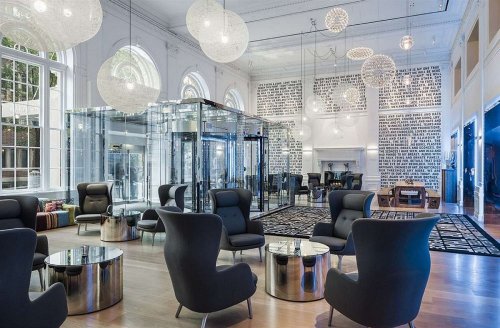 Modern lounge with stylish black chairs, glass display, and unique lighting in a spacious, well-lit room.
