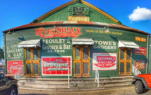 A vintage grocery and bar building with colorful signage, featuring a green wooden exterior and a welcoming porch.