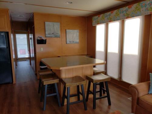 A cozy interior of a home featuring a wooden dining table with stools, light wood paneling, and large windows.
