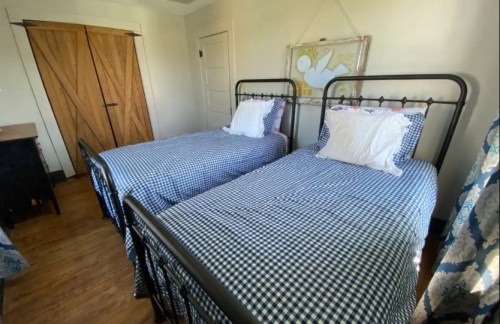 A cozy bedroom with two twin beds, each with blue and white checkered bedding, and wooden doors in the background.