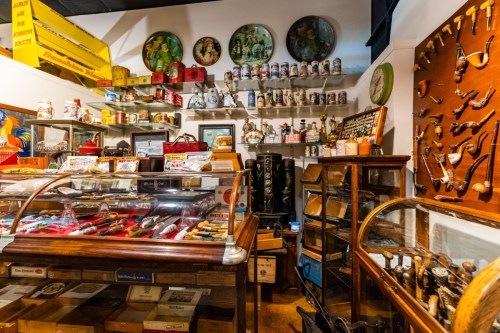 A vintage shop filled with collectibles, including glass displays, shelves of items, and decorative wall art.