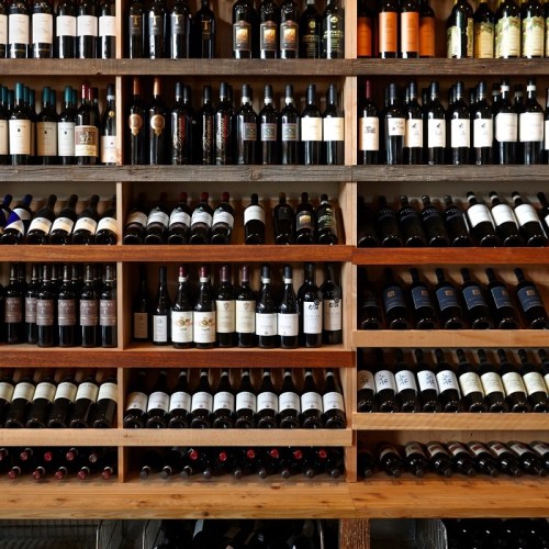 A wooden wine rack filled with various bottles of wine, organized by type and color.