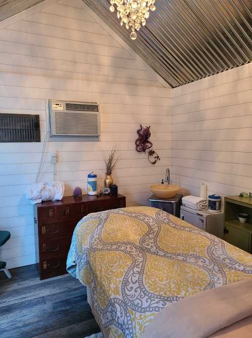 Cozy room with a bed, air conditioner, sink, and decorative elements, featuring a yellow patterned blanket and wooden furniture.