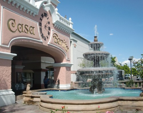 A large fountain in front of a pink building with "Casa Bonita" written above the entrance, under a clear blue sky.