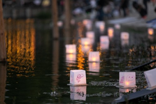 Floating lanterns with drawings, reflecting on water, create a serene evening atmosphere.