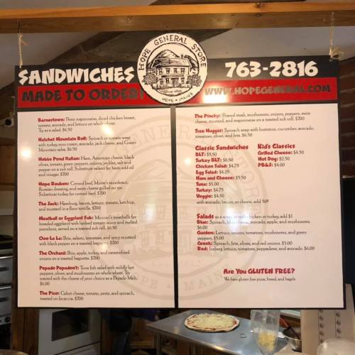 Menu board for a general store featuring various sandwich options and prices, with a contact number and website.