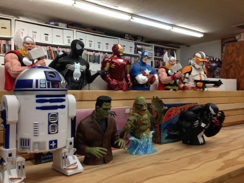 A collection of superhero and sci-fi figurines displayed on shelves in a comic book store.