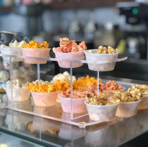 A display of colorful popcorn in clear cups, arranged on a tiered stand.