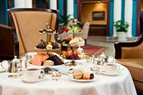 A beautifully arranged afternoon tea set with pastries, scones, and tea in an elegant setting.