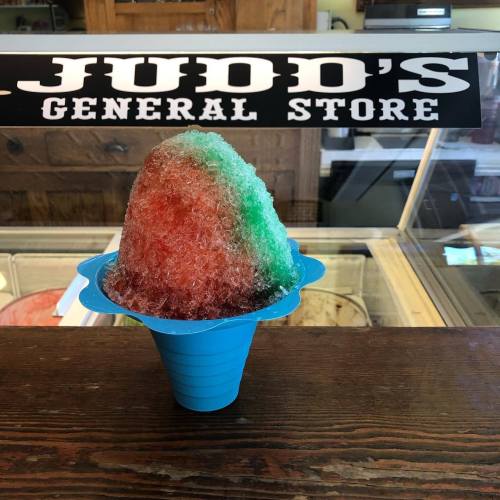 A colorful snow cone in a blue cup sits on a counter at Judd's General Store.