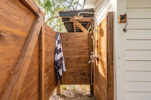 Outdoor shower enclosed by wooden walls, featuring a showerhead and a towel hanging on the side.