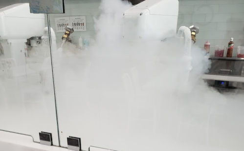 A kitchen scene with fog from dry ice, obscuring the view of equipment and condiments in the background.